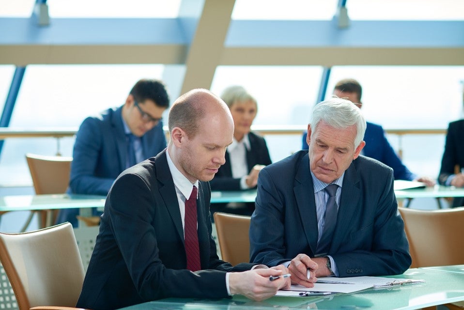 A group of men in suits looking at papers