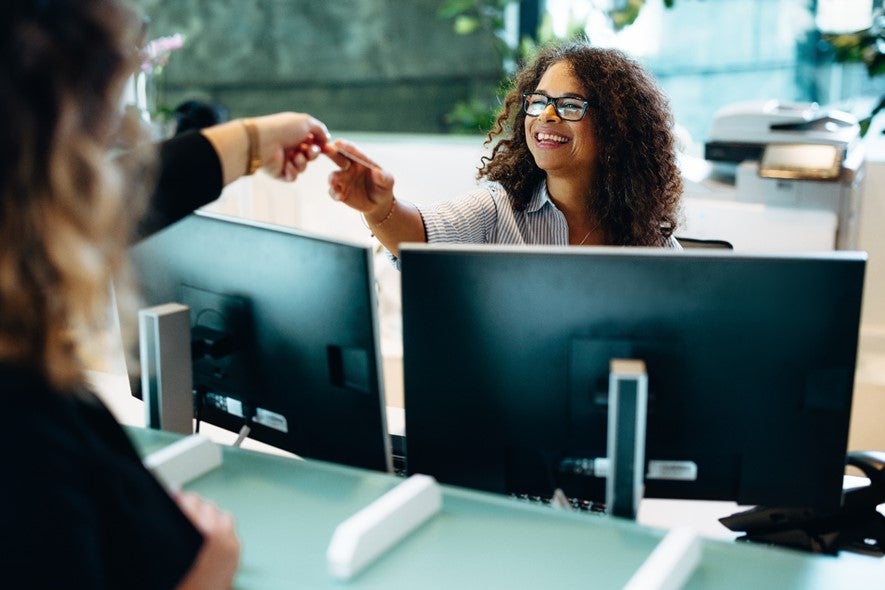 A person handing a card to a woman