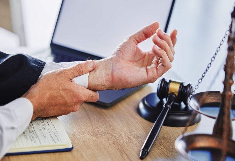 Person experiencing wrist pain related to repetitive motion injuries during work.