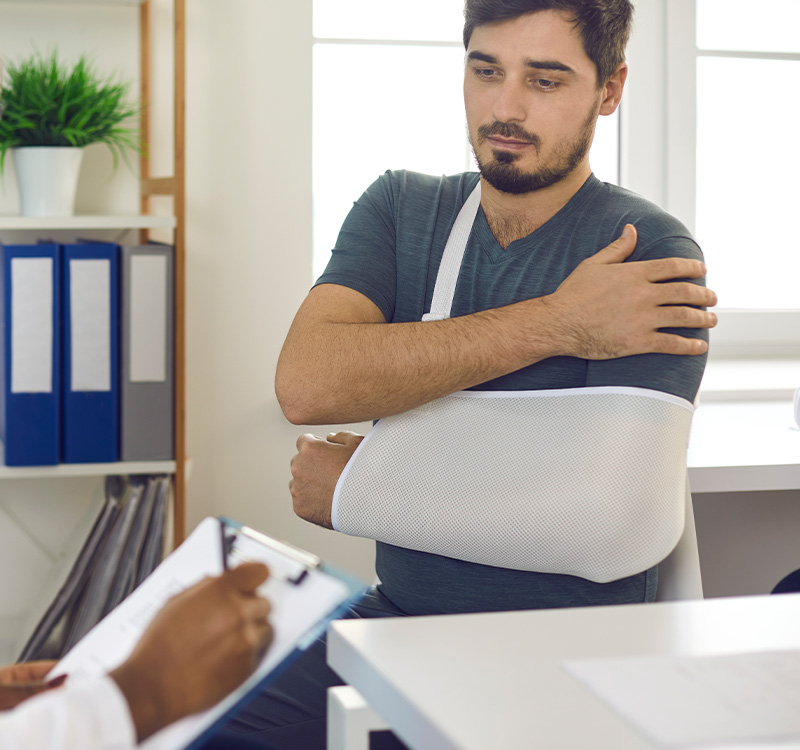 Doctor prescribing treatment to young patient with broken hand, wrist, elbow or arm