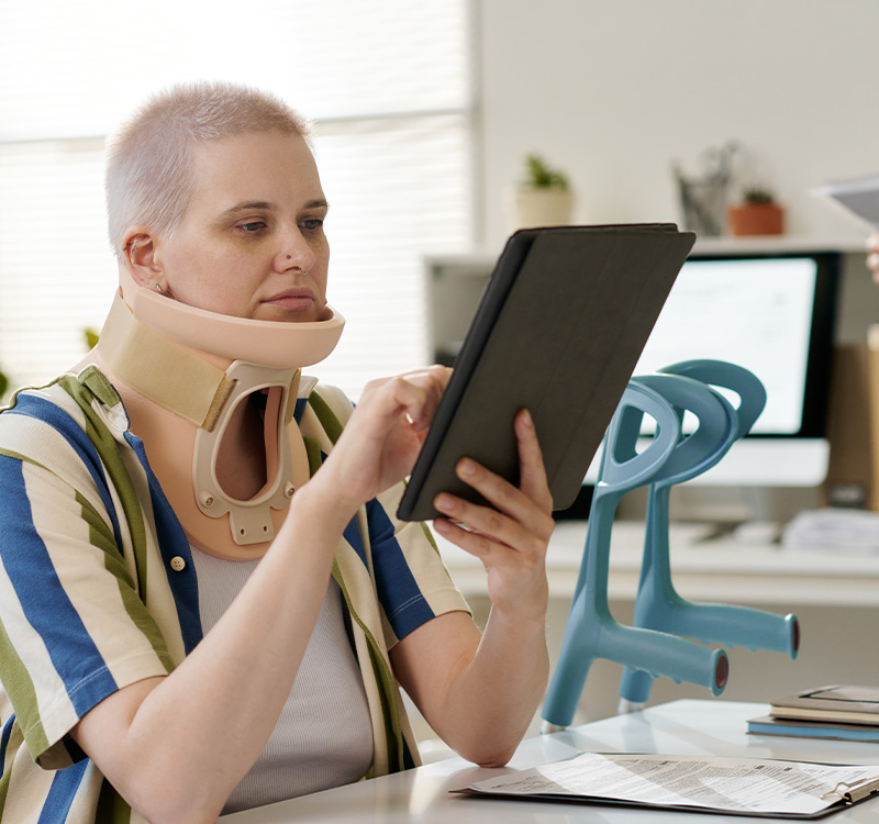 Woman with broken neck reading insurance benefits