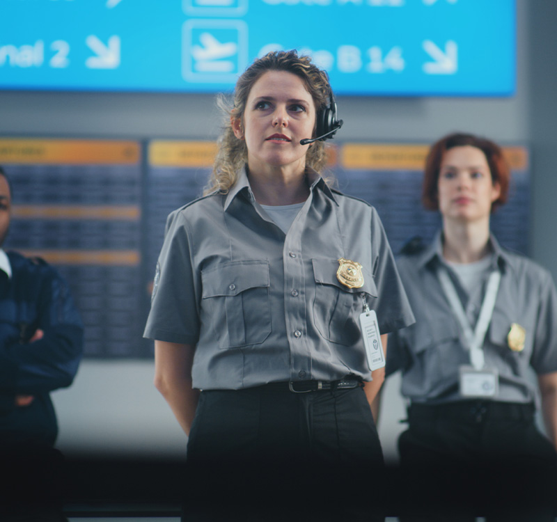 Female security officer wearing headset giving instructions to team of workers