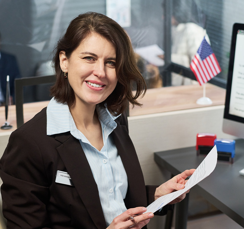 Middle aged woman smiling while holding documents at visa center desk