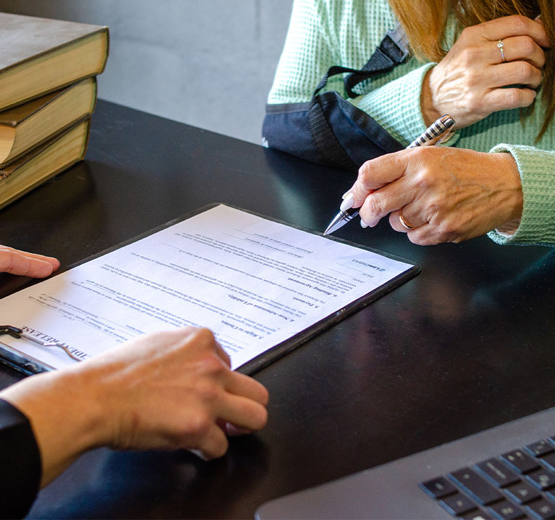 Close up of injured woman signing accident release form with lawyer